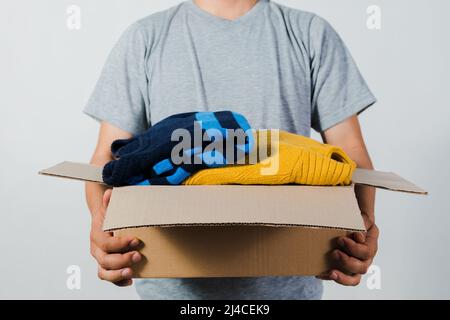 Mann, der eine Kiste mit gebrauchter Kleidung in der Hand hält Stockfoto