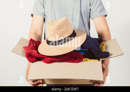 Mann, der eine Kiste mit gebrauchter Kleidung in der Hand hält Stockfoto