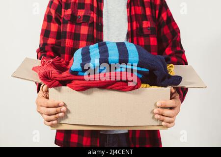 Mann, der eine Kiste mit gebrauchter Kleidung in der Hand hält Stockfoto