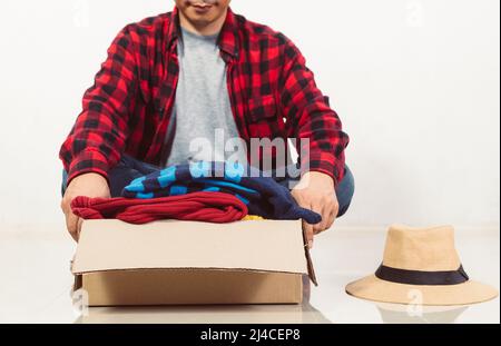 Mann, der eine Kiste mit gebrauchter Kleidung in der Hand hält Stockfoto