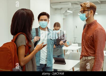 Männlicher Student im Gespräch mit seinen Freunden während einer Pause zwischen den Vorlesungen Stockfoto