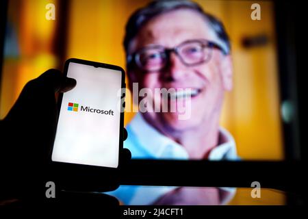 Microsoft-Logo auf dem Bildschirm und Bill Gates im Hintergrund. Er ist Mitbegründer von Microsoft Stockfoto