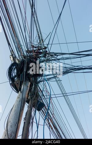 Strommasten mit überfüllten Drähten und Verteilerkästen in Indien. Stockfoto