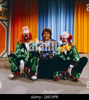 1, 2 oder 3, ZDF Quizshow für Kinder, moderiert von Michel Schanze, auf dem Bild mit zwei Clowns, Deutschland, 1981. 1, 2 oder 3, TV-Quizshow für Kinder, präsentiert von Michael Schanze, auf dem Foto mit zwei Clowns, Deutschland, 1981. Stockfoto