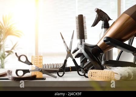 Friseurwerkzeuge auf weißer Werkbank mit Fenster im Hintergrund. Vorderansicht. Horizontale Zusammensetzung. Stockfoto