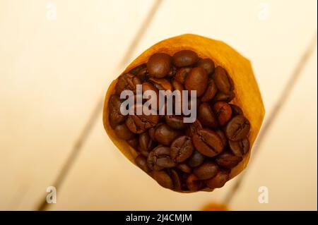 Espresso-Kaffeebohnen auf einem Papierkegel Füllhorn auf weißem Hintergrund Stockfoto