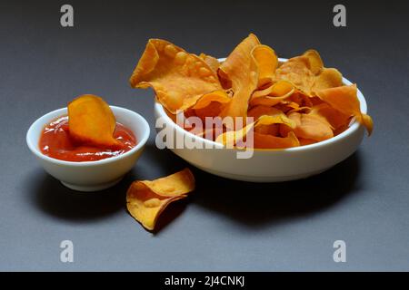 Süße Chips und Schale mit Tomatenketchup, Süßkartoffel (Ipomoea batatas) Stockfoto