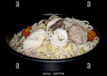 Lebensmittelfotografie, Asiatische Suppe mit Tintenfisch, Mien-Nudeln, Kohlstreifen, Fleischbällchen, Tomaten, Pilze und Kokosmilch Stockfoto