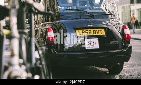 Greater London, London, Großbritannien - 12. April 2022: Ein klassisches schwarzes Londoner Taxi, aufgenommen auf einer Londoner Straße. Das Nummernschild ist als Fahrerhaus-Pas sichtbar Stockfoto