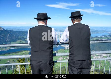 Zwei Männer in traditionellen Sängerkostümen genießen den Blick auf das Stanserhorn, Kanton Nidwalden, Schweiz Stockfoto