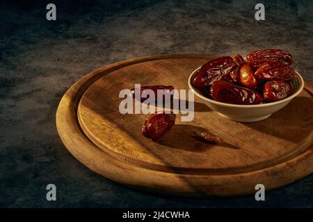 Getrocknete Datteln in einer Keramikschale auf einem Holzbrett Stockfoto