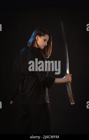 Geheimnisvolle junge schöne Frau mit scharfer Klinge im asiatischen Stil. Stockfoto