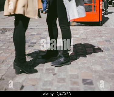 Covent Garden, London, Großbritannien - 12. April 2016: Zwei Menschen (mit der Hüfte nach unten) können auf einer gepflasterten Londoner Straße stehen und interagieren. Stockfoto