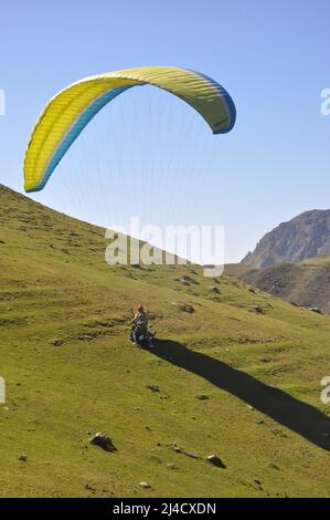 Nicht identifizierter Pilot-Fallschirm auf dem Berg mit einem Touristen Stockfoto