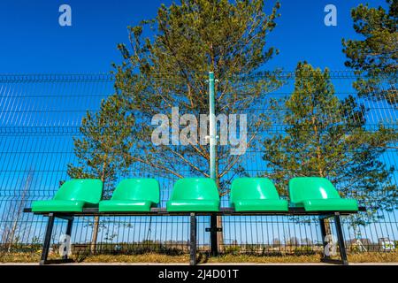 Leere Plastikstühle im Basketballfeld im Freien aus einem niedrigen Winkel Stockfoto