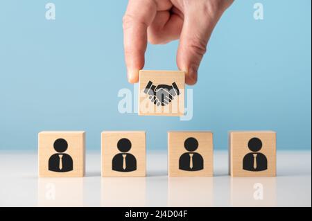 Geschäftsvertrag. Hand Putting Hand Schütteln, die Bildschirm auf Holzwürfelblock vor der menschlichen Ikone für Business Deal und Vereinbarung Konzept drucken. T Stockfoto