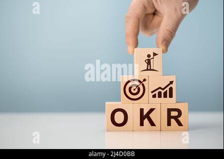 OKR Objectives, Key und Results Holzwürfelblöcke auf blauem Hintergrund. Geschäftsziel und Förderung von Geschäft und Leistung. Konzentrieren Sie sich auf das Ziel. Projekt-Mana Stockfoto
