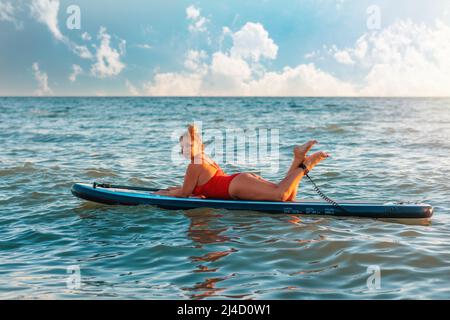 Plus Größe schöne kaukasische Frau in roten Badeanzug posiert auf einem Brett liegen. Das Konzept von Sport und Sommerurlaub. Stockfoto