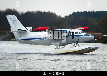 Das zweimotorige Wasserflugzeug ein Wasserflugzeug steigt aus dem Wasser, aus dem Waldsee, dem nördlichen Land auf. Wasserflugzeug Stockfoto