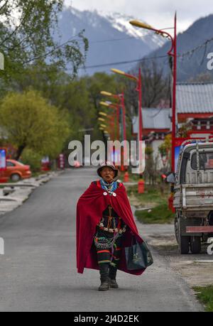 (220414) -- LHASA, 14. April 2022 (Xinhua) -- Yabao, 74, geht auf einer Straße in der ethnischen Gemeinde Namyi Lhoba im Landkreis Mainling, südwestlich der Autonomen Region Tibet, 12. April 2022. Lhoba, eine ethnische Gruppe im Südosten Tibets, ist eine der kleinsten unter den 56 ethnischen Gruppen Chinas, was die Bevölkerung angeht. Die Lhoba haben ihre eigene gesprochene Sprache, aber keine schriftliche Form. Die Legende der Vorfahren von Lhoba wurde 2011 als nationales immaterielles Kulturerbe aufgeführt. (Xinhua/Sun Fei) Stockfoto