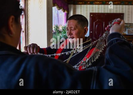 (220414) -- LHASA, 14. April 2022 (Xinhua) -- Yabao, 74, zieht traditionelle Lhoba-Kleidung in der ethnischen Gemeinde Namyi Lhoba im Landkreis Mainling, südwestlich der Autonomen Region Tibet, an, 12. April 2022. Lhoba, eine ethnische Gruppe im Südosten Tibets, ist eine der kleinsten unter den 56 ethnischen Gruppen Chinas, was die Bevölkerung angeht. Die Lhoba haben ihre eigene gesprochene Sprache, aber keine schriftliche Form. Die Legende der Vorfahren von Lhoba wurde 2011 als nationales immaterielles Kulturerbe aufgeführt. (Xinhua/Jigme Dorje) Stockfoto