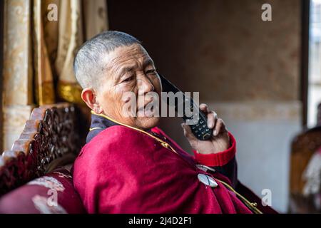 (220414) -- LHASA, 14. April 2022 (Xinhua) -- Yabao, 74, telefoniert in der ethnischen Gemeinde Namyi Lhoba im Landkreis Mainling, südwestlich der Autonomen Region Tibet, am 12. April 2022. Lhoba, eine ethnische Gruppe im Südosten Tibets, ist eine der kleinsten unter den 56 ethnischen Gruppen Chinas, was die Bevölkerung angeht. Die Lhoba haben ihre eigene gesprochene Sprache, aber keine schriftliche Form. Die Legende der Vorfahren von Lhoba wurde 2011 als nationales immaterielles Kulturerbe aufgeführt. (Xinhua/Sun Fei) Stockfoto