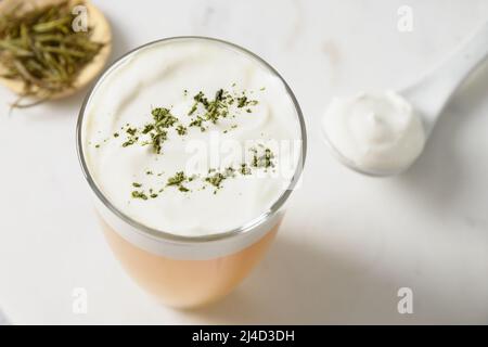 Traditioneller chinesischer Tee mit einer Schicht aus cremigem Matcha-Pulver auf weißem Hintergrund. Asiatische trendige Getränke. Thailändischer Milchtee. Nahaufnahme. Stockfoto
