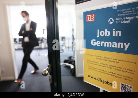 Köln, Deutschland. 14. April 2022. Ein Mann kommt an einem Plakat vorbei, auf dem „Job in Germany“ in einer Arbeitsberatung am Hauptbahnhof steht. Die Deutsche Bahn und die Agentur für Arbeit haben gemeinsam in der Nähe der Bahnhöfe in Köln, Berlin und Frankfurt Arbeitsberatungsstellen für ukrainische Flüchtlinge eingerichtet. Quelle: Oliver Berg/dpa/Alamy Live News Stockfoto