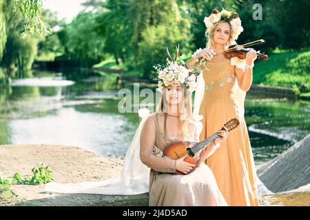 Duett von Frauen, die in der Natur Gitarre und Violine spielen Stockfoto