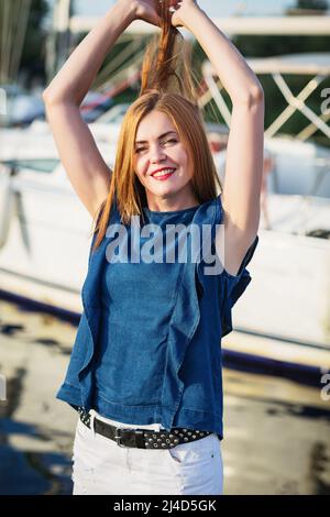 Eine pritty Frau, die an einem sonnigen Sommertag am Fluss auf der Marina posiert Stockfoto