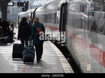 Köln, Deutschland. 14. April 2022. Reisende laufen am Hauptbahnhof zu einer Bahn der Deutschen Bahn. Kurz vor Karfreitag setzt die Deutsche Bahn weitere Züge ein, um den erwarteten Ansturm der Osterreisen besser zu bewältigen. Quelle: Roberto Pfeil/dpa/Alamy Live News Stockfoto