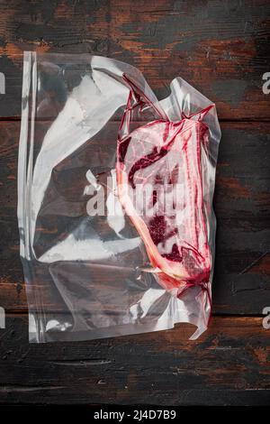 Frisches marmoriertes Fleisch schwarzes angus Steak in Vakuum-Plastiktüte für Sous Vide Set, auf altem dunklen Holztischhintergrund, Draufsicht flach liegend Stockfoto