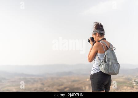 Anonyme Frau mit Rucksack, die in den Bergen fotografiert Stockfoto