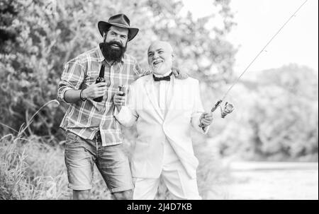 Prost. Männer entspannende Natur Hintergrund. Spaß und Entspannung. Am Wochenende. Angelkenntnisse. Die Stange mit der Hakenlinse aufsetzen. Angeln und Bier trinken Stockfoto