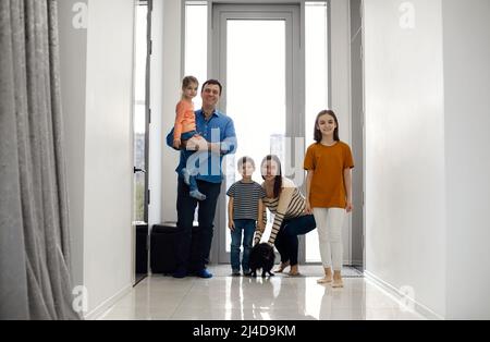 Aufgeregte Kinder, die mit ihren Eltern nach Hause kommen. Kinder nach Hause mit Eltern Mama und Papa, lächelnd niedlichen Kinder Bruder und Schwestern, Eingabe ein Stockfoto