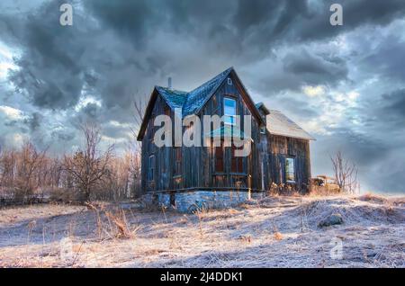 Ein altes, verlassene, gruselig aussehendes Bauernhaus im Winter auf einem Bauernhof im ländlichen Kanada Stockfoto