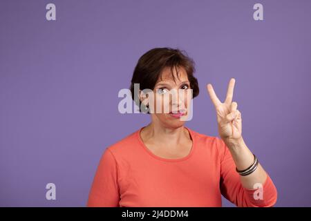 Studio Set im mittleren Alter Frau, mit zwei Fingern Stockfoto