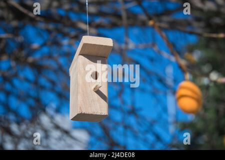 In einem kleinen Dekor befinden sich Holzvögel mit Kästen und Osterdekorationen, die an Ästen hängen Stockfoto