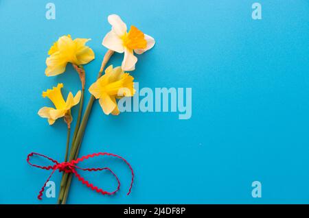 Narzissen in flachem Lay-Stil auf blauem strukturiertem Papier mit negativem Platz für Text Stockfoto