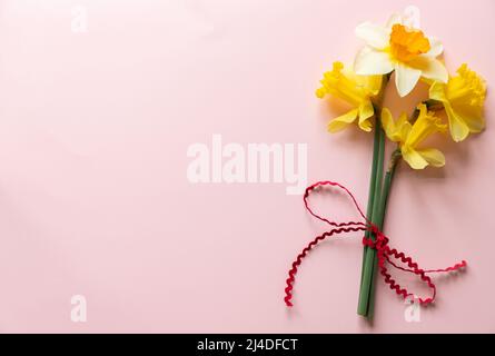 Narzissen in flachem Lay-Stil auf rosa strukturiertem Papier mit negativem Platz für Text Stockfoto