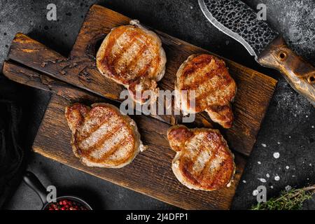 Gegrilltes Schweinesteak Filet Fleisch Set, auf schwarzem dunklem Steintisch Hintergrund, Draufsicht flach gelegen Stockfoto