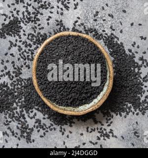 Indische Gewürze Schwarzkümmel (Nigella sativa oder Kalonji) Samen in Schale auf grauer Tischansicht. Traditionelle Medizin, gesundes und vegetarisches Lebensmittelkonzept. Stockfoto