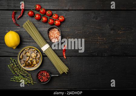 Zutaten für die Zubereitung von Spaghetti mit Beruhigung oder Muscheln, auf schwarzem Holztischhintergrund, Draufsicht flach, mit Kopierraum für Text Stockfoto
