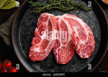 Frische Schweinehals-Fleischsteaks, auf altem dunklen Holztischhintergrund, Draufsicht flach liegend Stockfoto