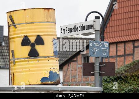 Salzgitter, Deutschland. 14. April 2022. Ein Fass mit einem bemalten Atomschild steht als Protestaktion neben einem Straßenschild mit der Aufschrift „am Feuerlöschbrunnen“ im Dorf Bleckenstedt bei Salzgitter nahe dem Schacht Konrad. Im bereits zugelassenen Endlager Schacht Konrad sollen niedrig- bis mittelradioaktive Abfälle gelagert werden. Kredit: Mia Bucher/dpa/Alamy Live Nachrichten Stockfoto