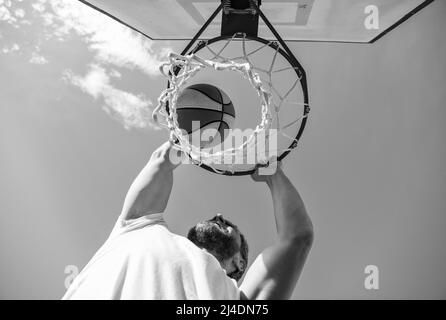 Guy dunking Basketball Ball durch Netzring mit Händen, gewinnen Stockfoto