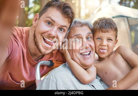 Viel Spaß für die ganze Familie. Beschnittenes Porträt eines hübschen jungen Mannes, der mit seinem Vater und seinem Sohn Selfies macht, während er im Wald kampiert. Stockfoto