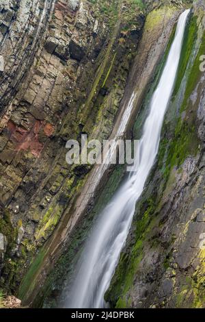 Der Wasserfall Speke's Mill Mouth liegt nur einen kurzen Spaziergang über die Klippen vom Hartland Quay entfernt. Die Wasserfälle stürzen 48 Meter von oben auf den Strand unten in t Stockfoto