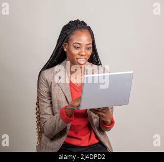 Schwarze Frau lächelt und hält einen Laptop. Afro-amerikanische Geschäftsfrau Konzept. Stockfoto