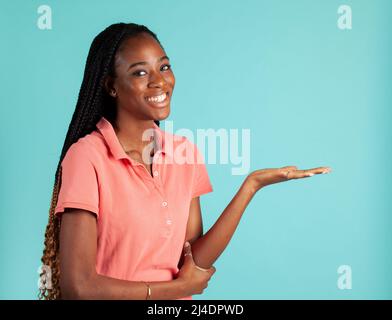 Afroamerikanische Frau mit umgesteldeter Palme. Sprecher posieren, Ihr Produkt in der Handfläche zu halten. Stockfoto